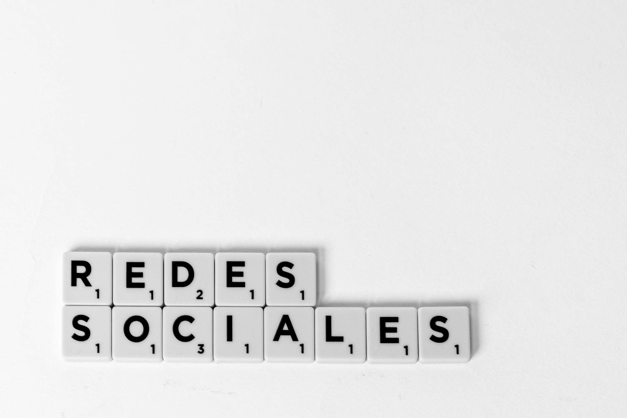 Scrabble tiles spelling 'Redes Sociales' illustrating a social media concept on a white background.